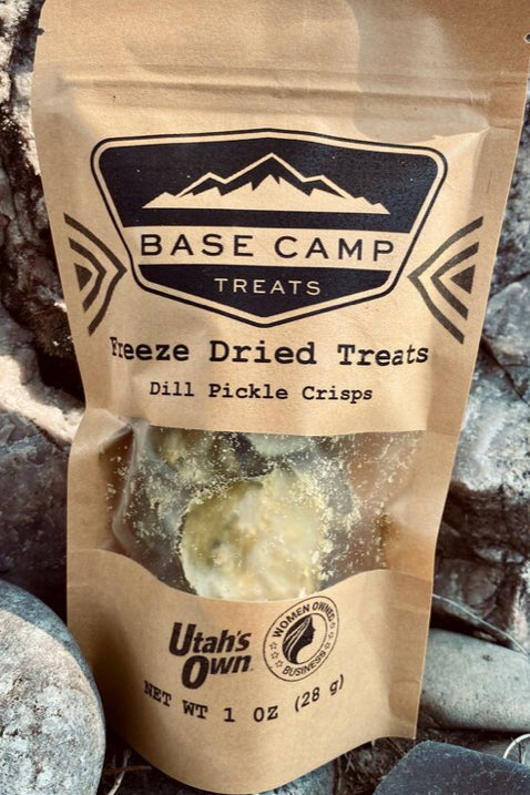 Base Camp Treats freeze-dried dill pickle crisps packaging on a rocky surface