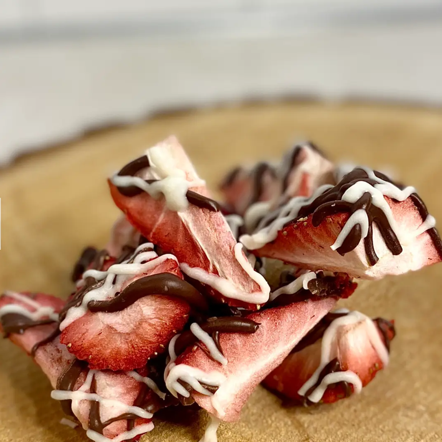 Base Camp Treats Freeze Dried Strawberry Bark on a wooden coaster on a  white background