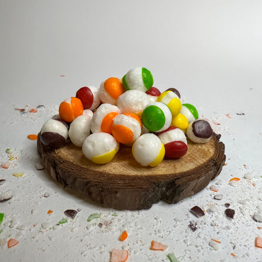 Base Camp Treats Rainbow Bites Freeze Dried Skittles on wood disk and a white background
